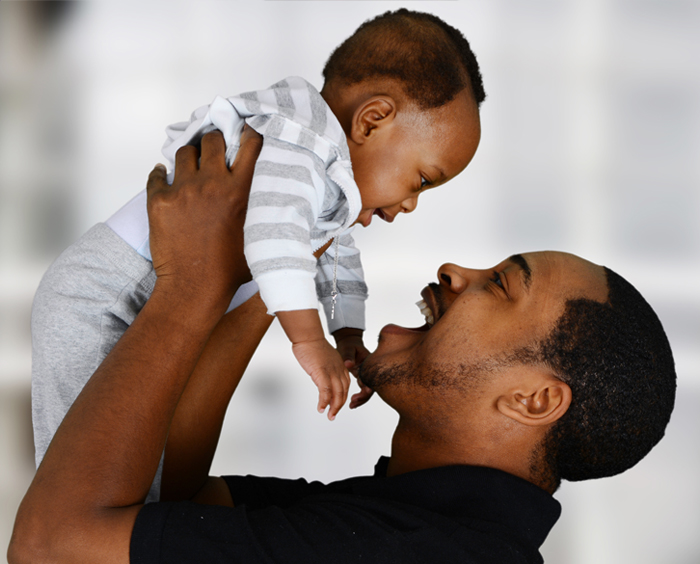 Smiling father holding up toddler