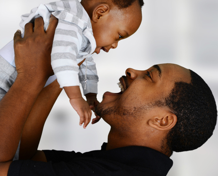 Smiling father holding up toddler