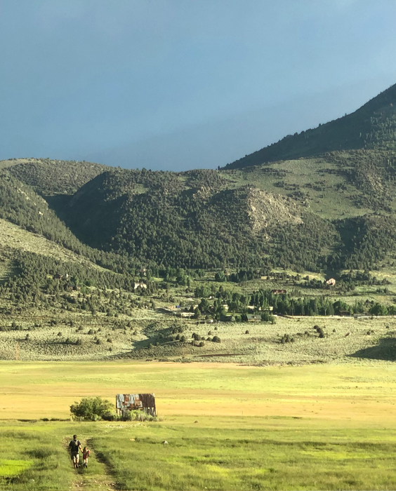 Grand mountain valley landscape with two people walking on the foreground